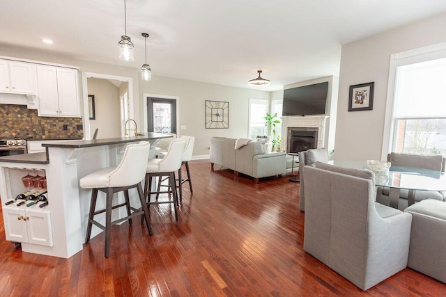 kitchen featuring white cabinetry, a breakfast bar, dark wood-style flooring, dark countertops, and open floor plan