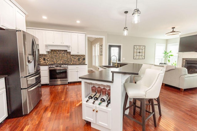 kitchen with dark wood-type flooring, dark countertops, stainless steel appliances, open floor plan, and custom range hood
