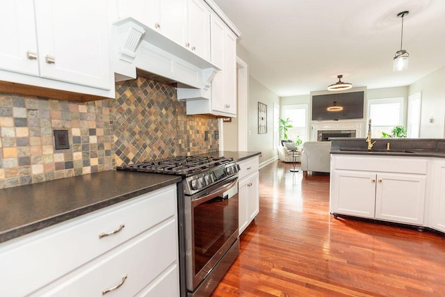 kitchen featuring open floor plan, stainless steel gas range, dark countertops, and decorative backsplash