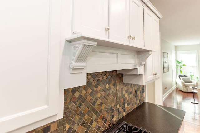 interior details featuring white cabinetry, wood finished floors, and backsplash