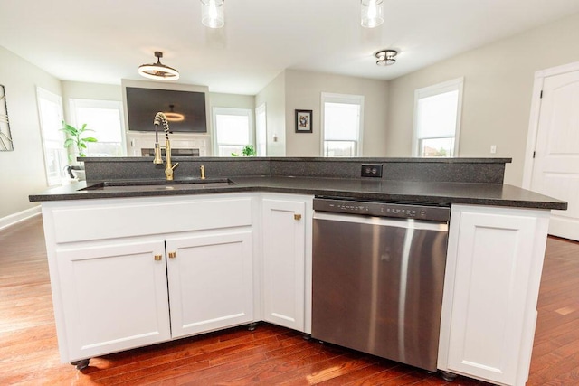 kitchen featuring white cabinets, dark wood-type flooring, dark stone counters, stainless steel dishwasher, and a sink