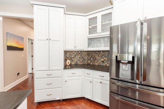 kitchen with white cabinets, dark countertops, stainless steel fridge, decorative backsplash, and dark wood-style floors