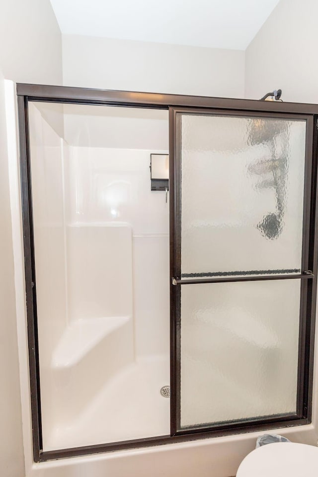 bathroom with toilet and a stall shower
