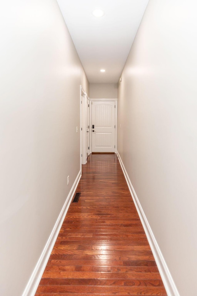 hall with visible vents, baseboards, recessed lighting, and wood finished floors