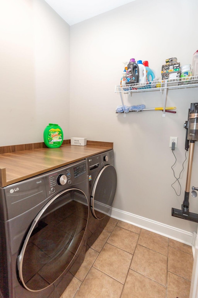 washroom featuring laundry area, baseboards, tile patterned flooring, and washing machine and dryer