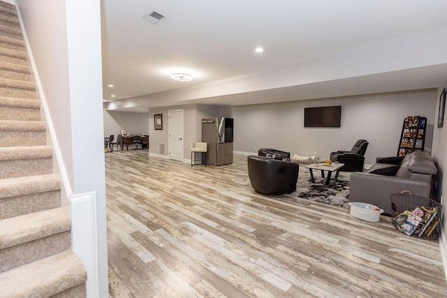 living room with light wood-style floors, visible vents, recessed lighting, stairway, and baseboards