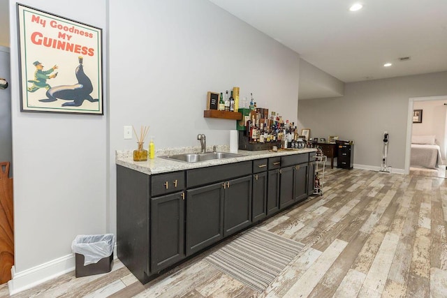 bar with baseboards, wet bar, recessed lighting, light wood-style flooring, and a sink