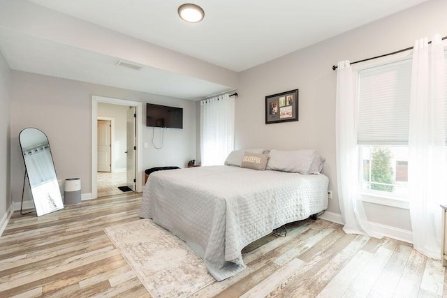 bedroom with light wood-style flooring, baseboards, and visible vents