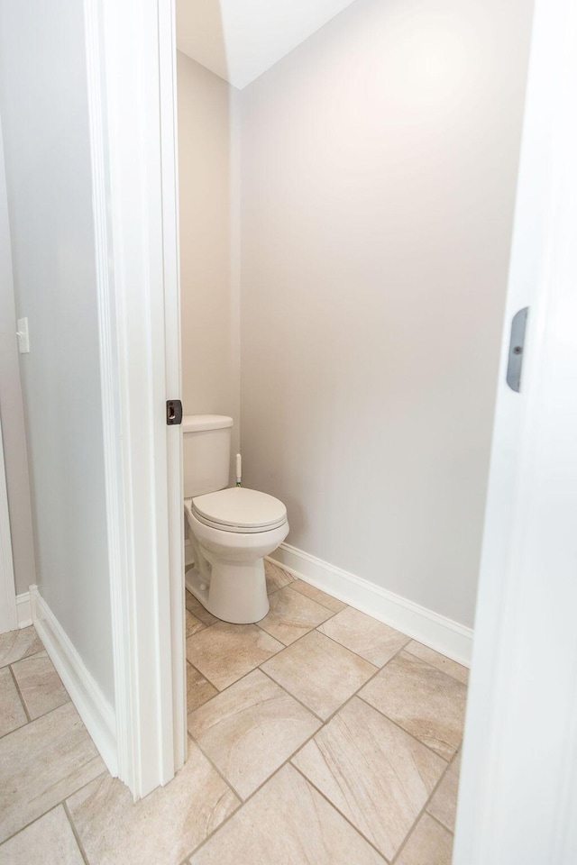 bathroom featuring toilet, tile patterned floors, and baseboards
