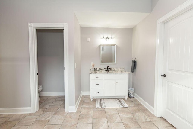 bathroom featuring toilet, vanity, and baseboards