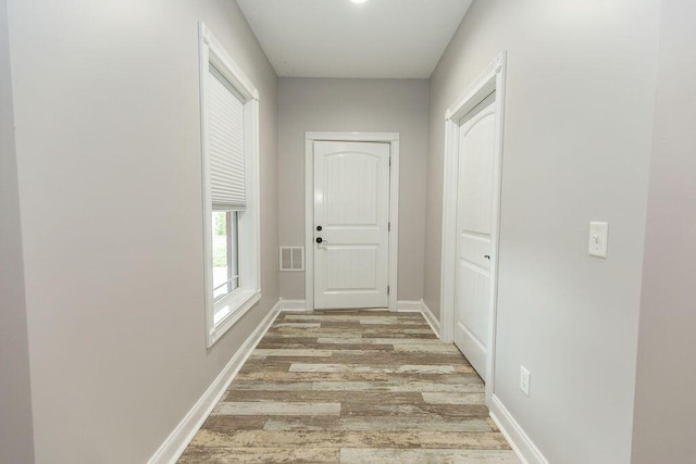 hallway featuring visible vents, baseboards, and light wood-type flooring
