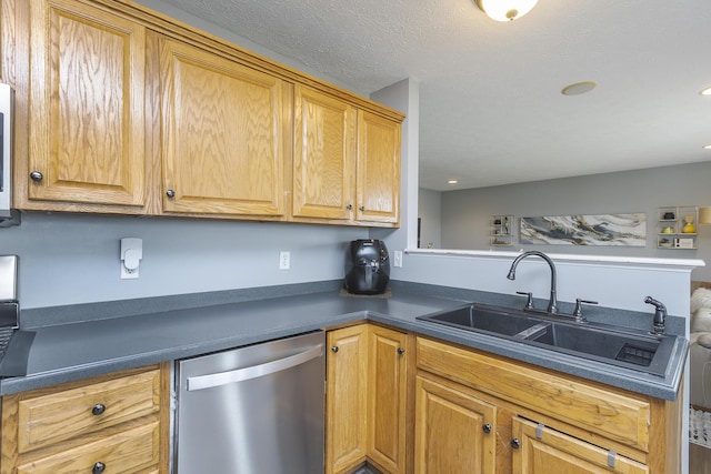 kitchen featuring recessed lighting, dark countertops, dishwasher, a sink, and a peninsula