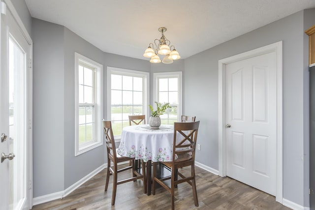 dining space featuring an inviting chandelier, wood finished floors, and baseboards