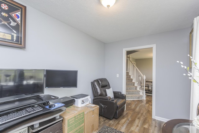 living area with wood finished floors, a textured ceiling, and stairway