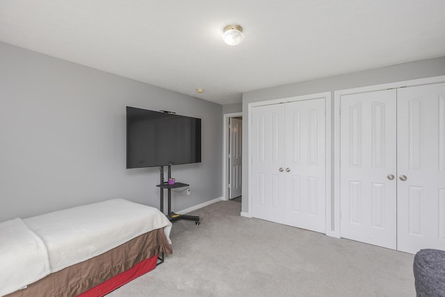 carpeted bedroom featuring two closets and baseboards