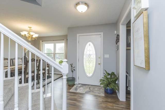 entrance foyer featuring stairway, an inviting chandelier, wood finished floors, and a textured ceiling