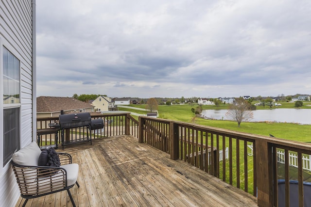 wooden terrace featuring a lawn and a water view