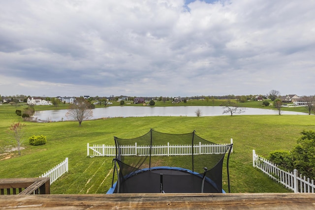 view of yard with fence, a water view, and a trampoline