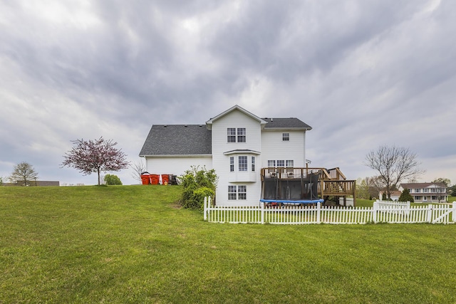 back of property with fence, a lawn, roof with shingles, and a deck