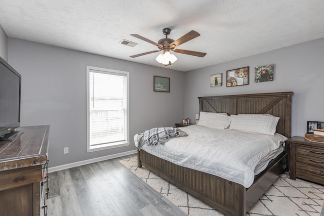 bedroom with baseboards, a ceiling fan, visible vents, and light wood-style flooring