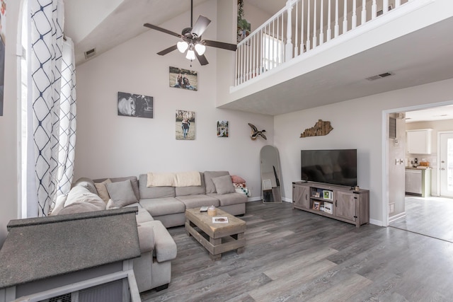 living area with ceiling fan, arched walkways, wood finished floors, and visible vents