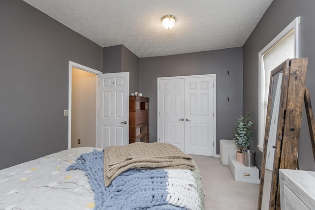 bedroom with light colored carpet, a textured ceiling, and a closet