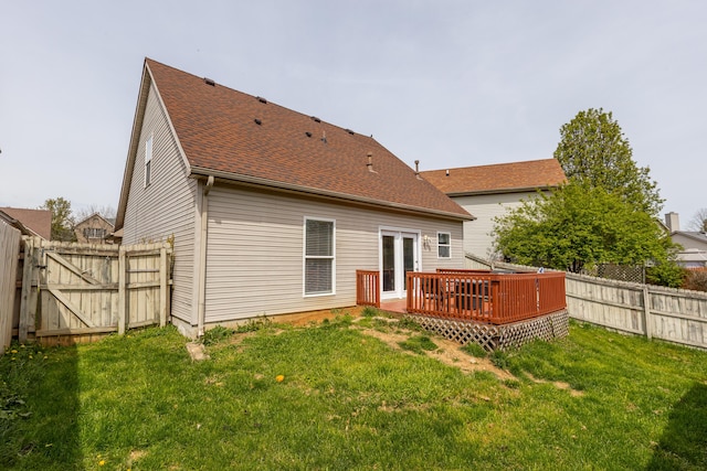 rear view of property featuring a gate, a deck, a shingled roof, a fenced backyard, and a yard