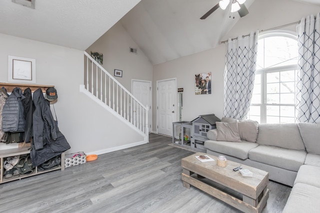 living room with stairway, vaulted ceiling, a ceiling fan, and wood finished floors
