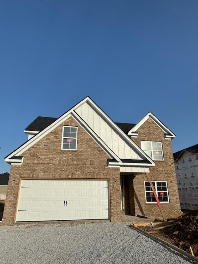 151 Village Park Dr, Georgetown, KY 40324 - view of front of house featuring gravel driveway, brick siding, board and batten siding, and an attached garage