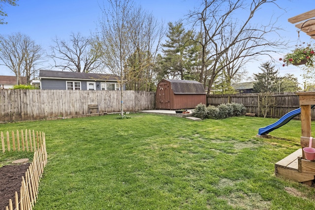 view of yard featuring an outdoor structure, a fenced backyard, and a storage shed