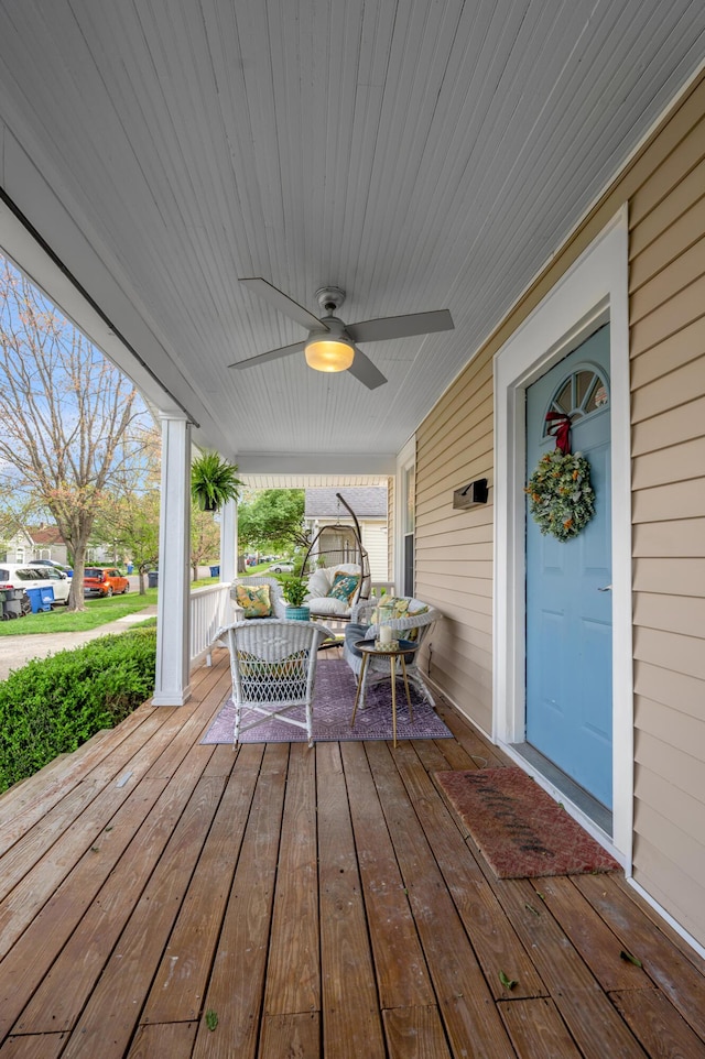 wooden terrace with a ceiling fan, covered porch, and an outdoor living space