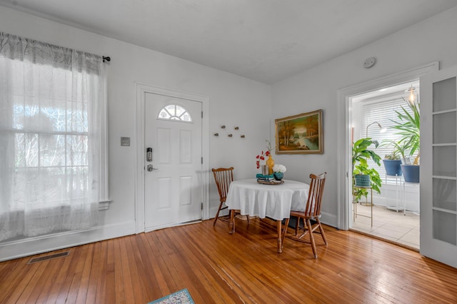 dining area featuring wood-type flooring, a healthy amount of sunlight, baseboards, and visible vents