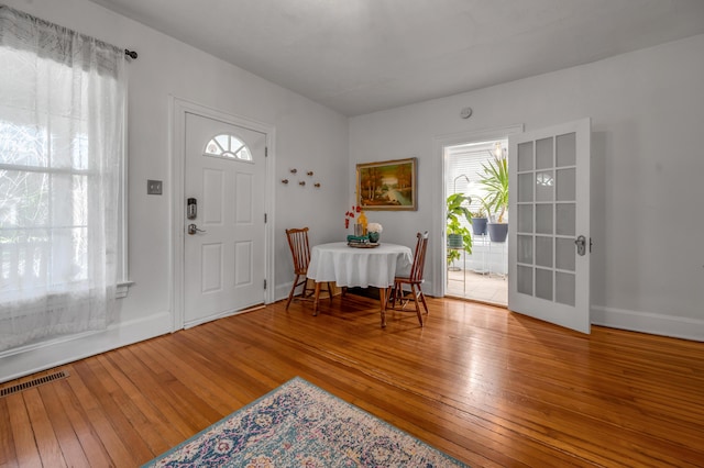 foyer entrance with baseboards, hardwood / wood-style floors, visible vents, and plenty of natural light