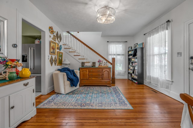 foyer entrance featuring visible vents, baseboards, light wood-style floors, and stairway