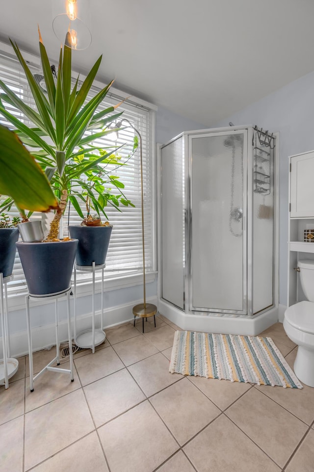 bathroom featuring a shower stall, toilet, tile patterned floors, and baseboards