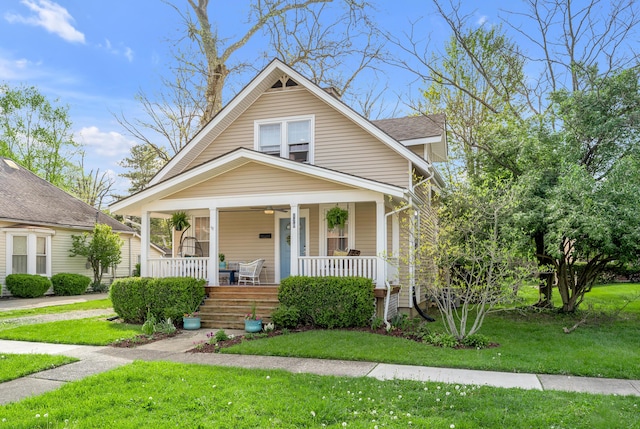 bungalow with a front lawn, covered porch, and roof with shingles