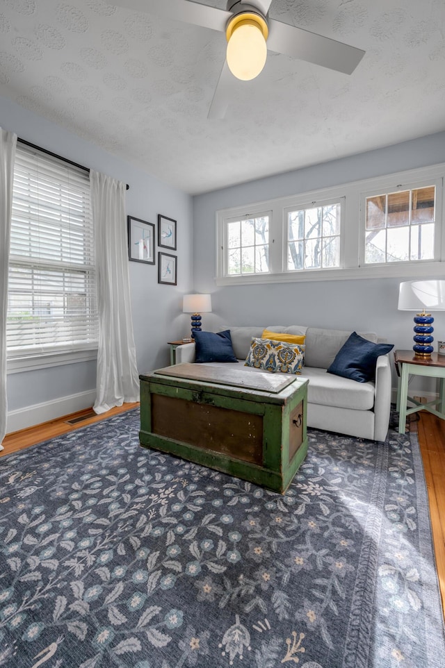 living area with ceiling fan, baseboards, and wood finished floors