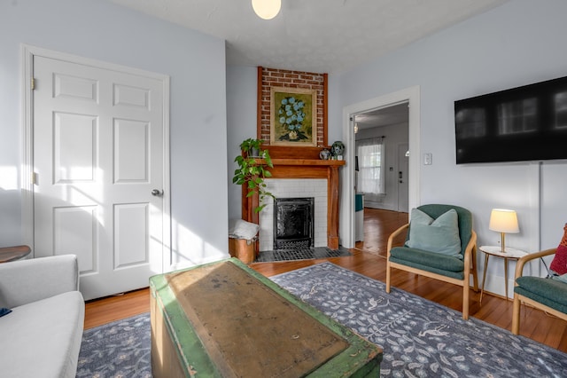 living area featuring a brick fireplace and wood finished floors