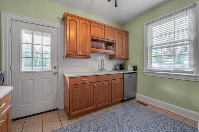 kitchen with brown cabinets, stainless steel dishwasher, a sink, and a wealth of natural light