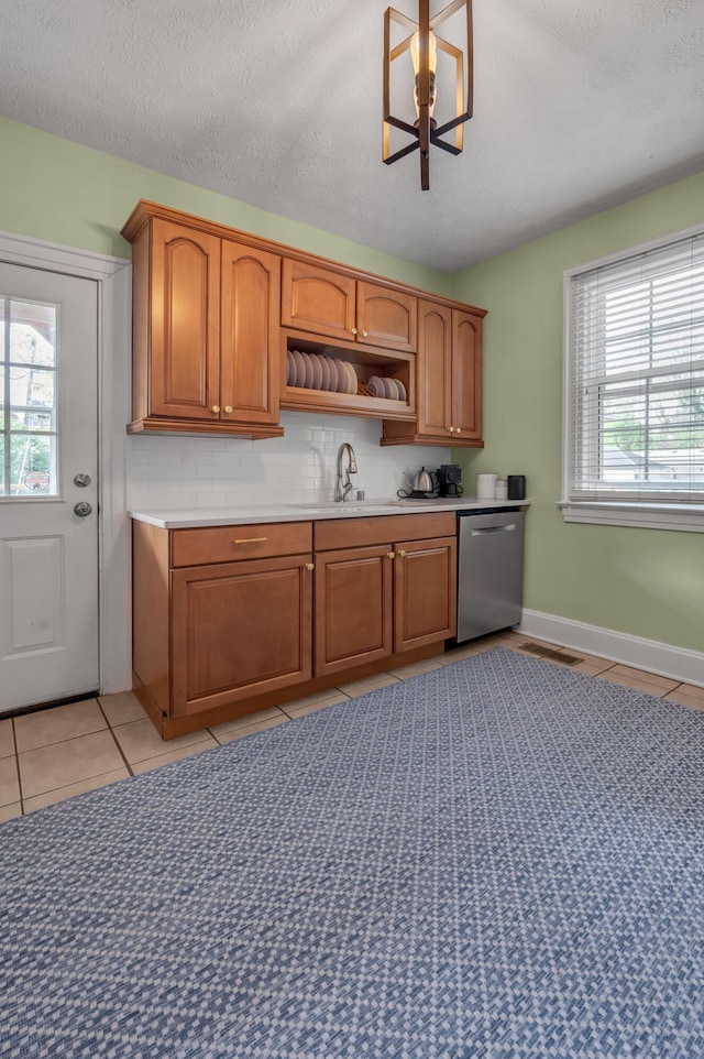 kitchen featuring tasteful backsplash, dishwasher, light tile patterned floors, and a sink