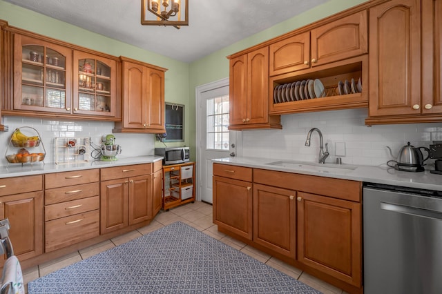kitchen with stainless steel appliances, a sink, tasteful backsplash, brown cabinets, and light countertops