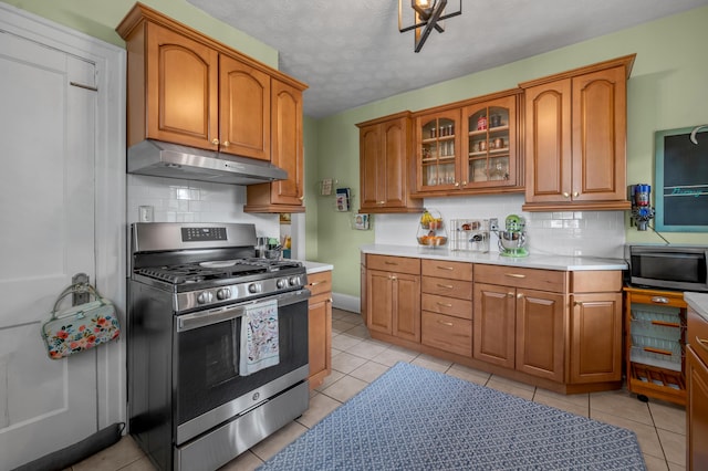 kitchen featuring backsplash, brown cabinets, under cabinet range hood, and stainless steel appliances