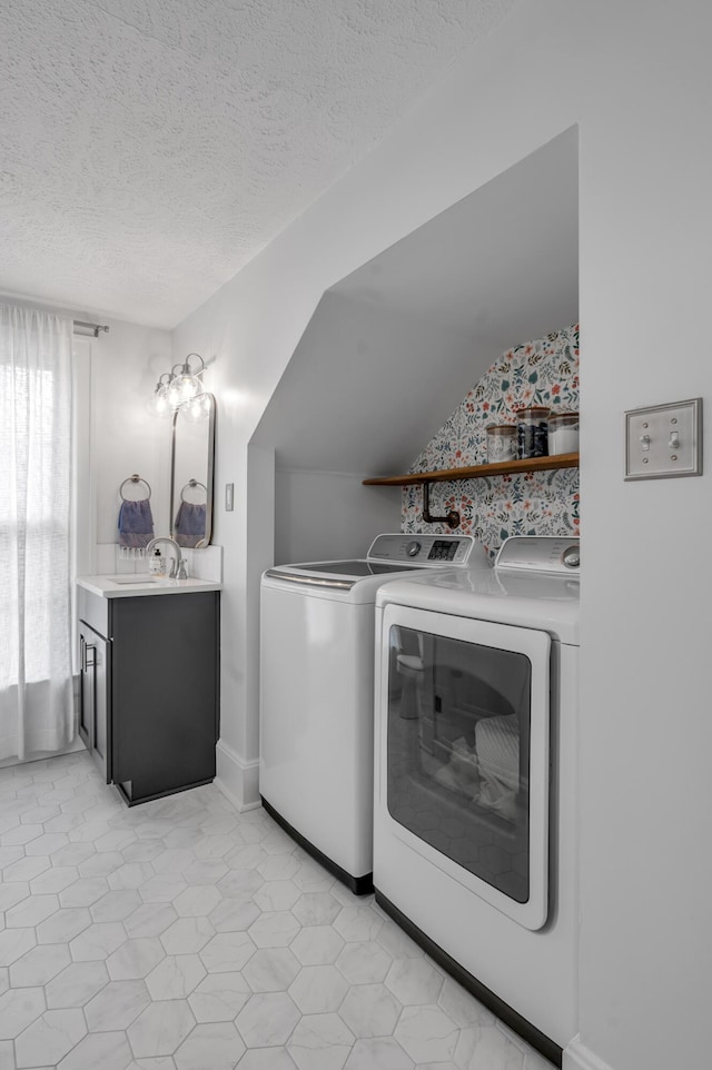 laundry area featuring washing machine and clothes dryer, a textured ceiling, a sink, baseboards, and laundry area