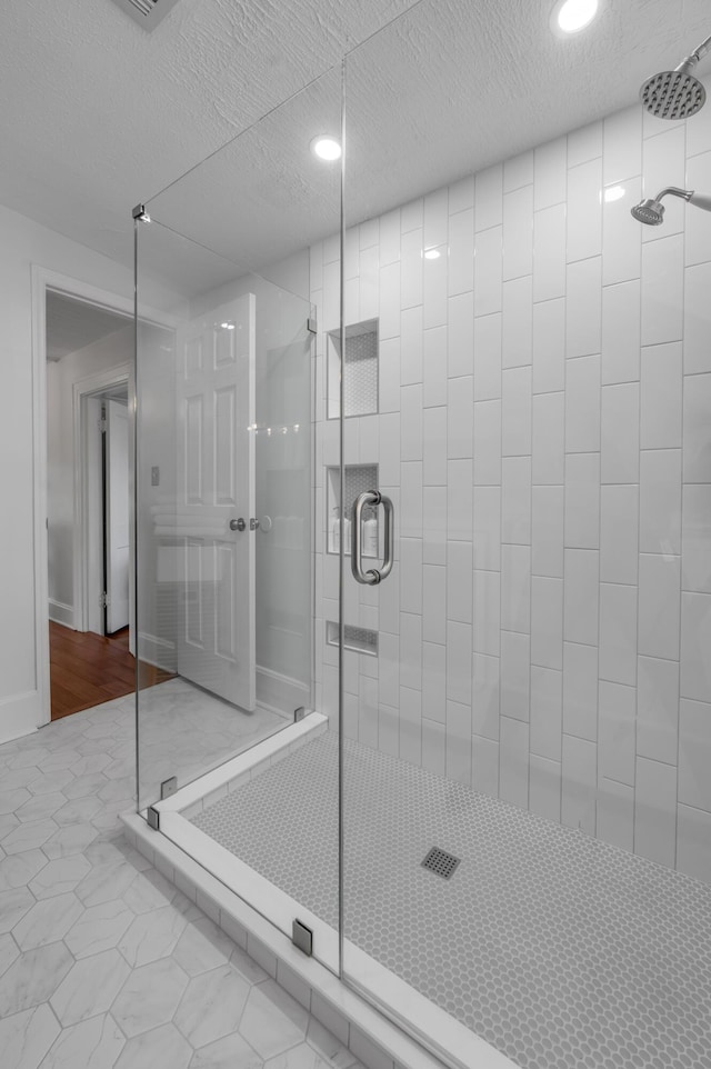 bathroom featuring recessed lighting, a textured ceiling, and a stall shower