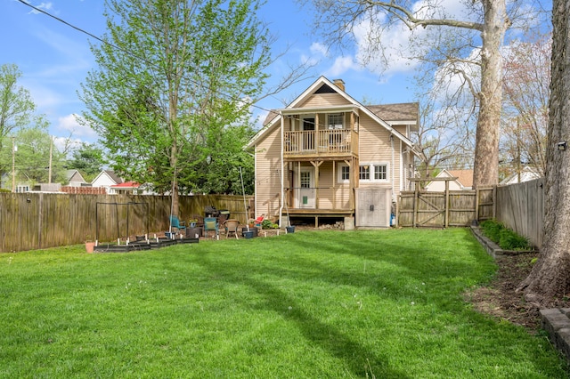 back of property featuring a lawn, a chimney, a fenced backyard, and a balcony