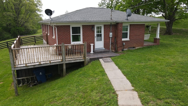back of property with roof with shingles, a deck, a yard, and brick siding