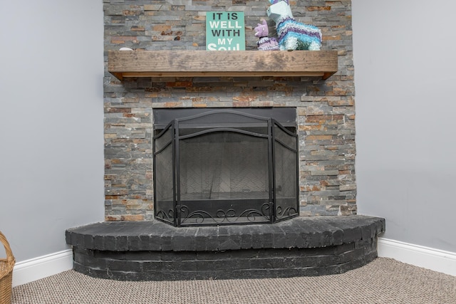 details with a fireplace with raised hearth, carpet flooring, and baseboards