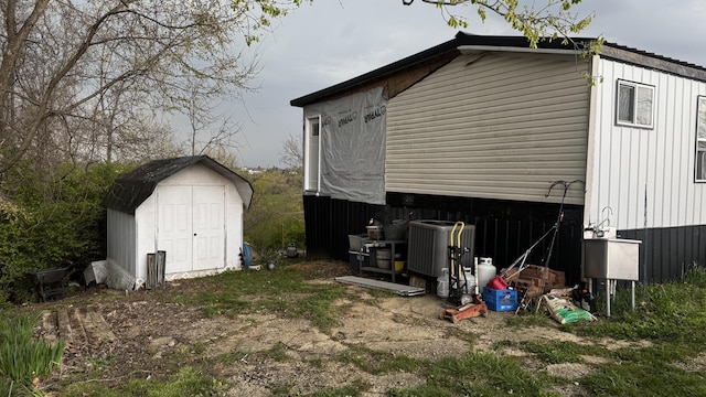 view of side of home featuring a storage shed, central AC, and an outdoor structure