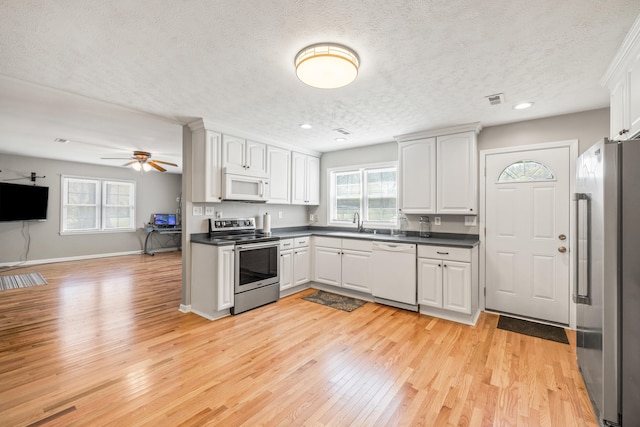 6473 Wildie Rd, Mount Vernon, KY 40456 - kitchen with dark countertops, appliances with stainless steel finishes, light wood-style floors, and a textured ceiling