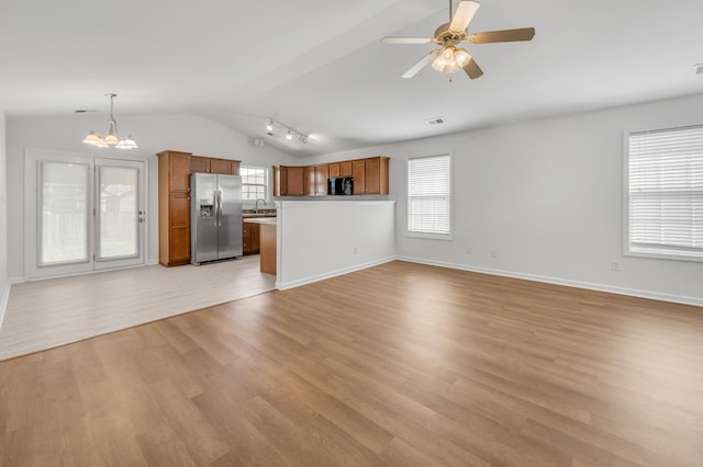 unfurnished living room featuring light wood-style flooring, a healthy amount of sunlight, a sink, and lofted ceiling